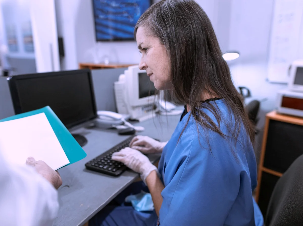Coordenadora de escalas gerenciando plantões em um monitor com grade de horários